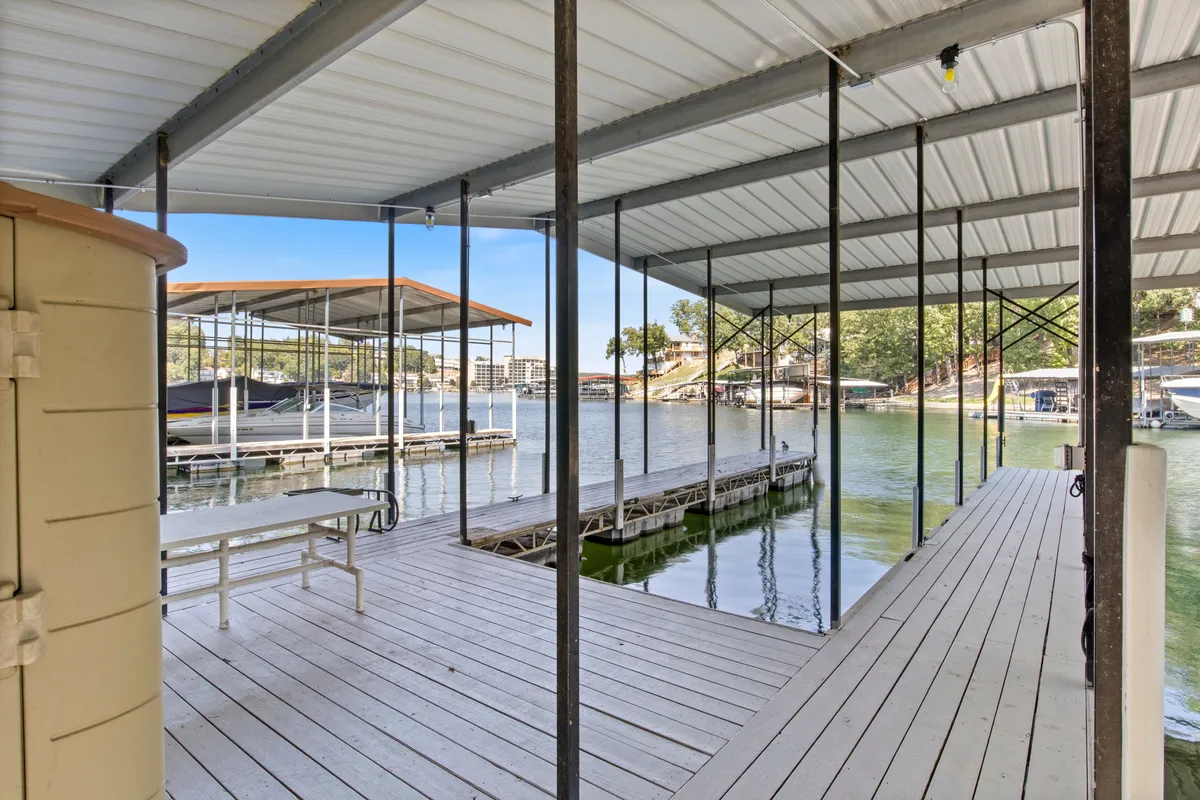 An inviting dock extends over calm water, framed by boats and lush trees. The area exudes peace and serves as a hub for boating, fishing, or evening bonfires—activities mentioned as key attractions in the section.