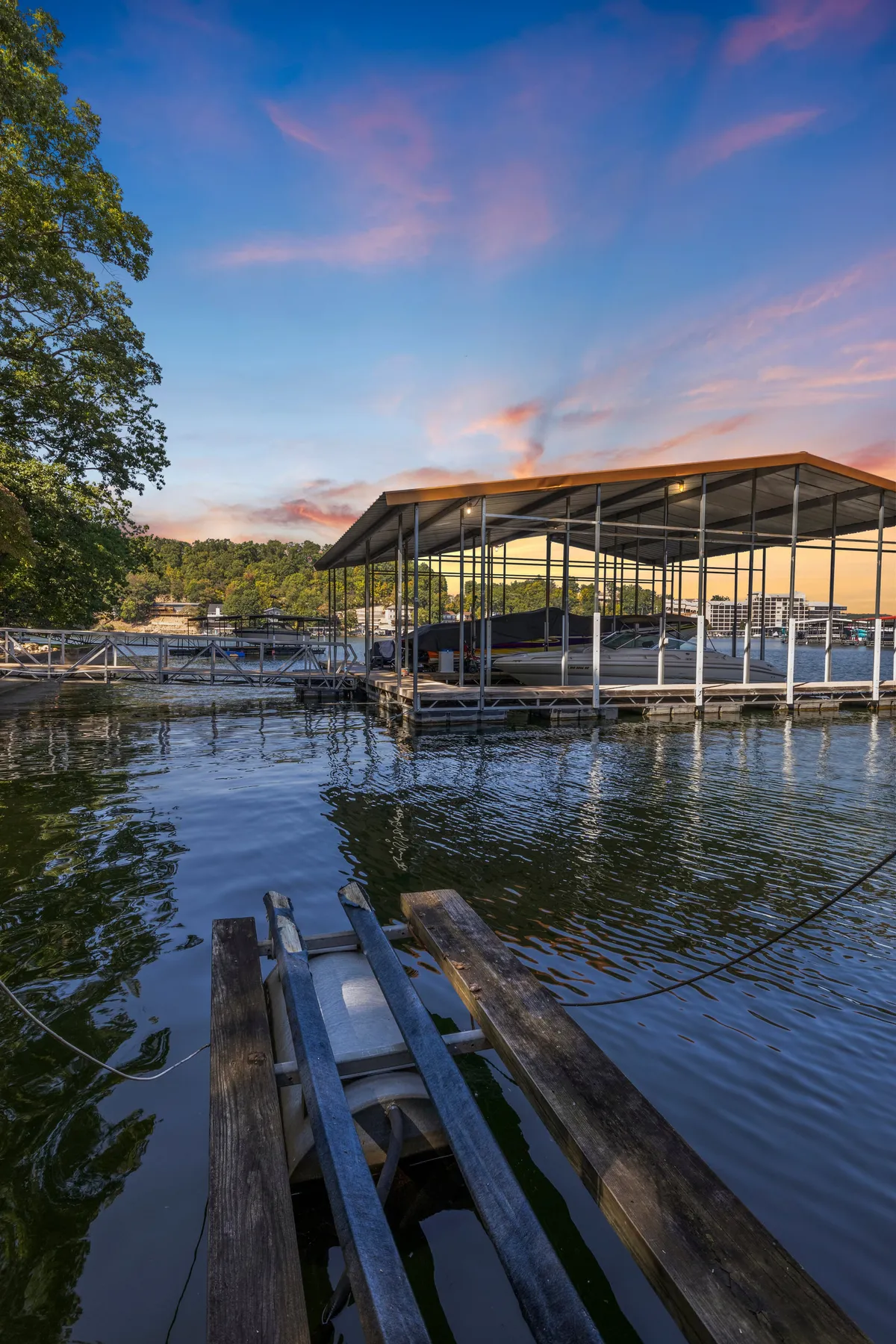 A tranquil view of the boathouse, calm water, and dock surrounded by trees. The image captures the peaceful atmosphere of the waterfront, ideal for unwinding after a lively evening or enjoying quiet moonlit moments by the lake.